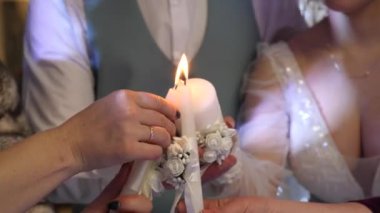 İki mum, ortadaki büyük olanı yakar. Aile ocağının taşınma ayini. Ulusal gelenekler.