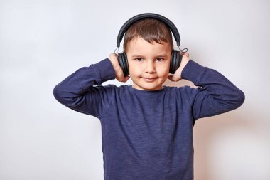 Yakışıklı bir çocuk kulaklıkla müzik dinler. Zevkle ve gülümseyerek..