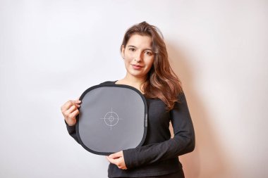 Gülümseyen güzel kız kameraya doğru renkleri kaydetmek için gri kart tutuyor..