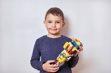 Yakışıklı, gülümseyen çocuk tasarımcının oyuncağını tutuyor..