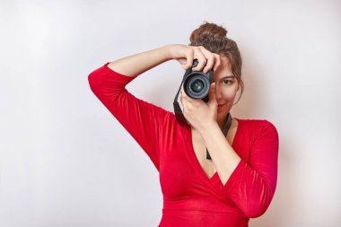 Pretty girl taking pictures with a digital camera holding it to her eye.