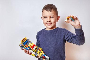 Yakışıklı, gülümseyen çocuk tasarımcının oyuncağını tutuyor..