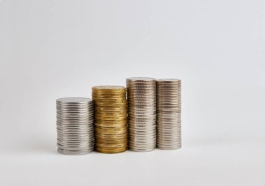 Four towers with coins of different denominations on a white background.