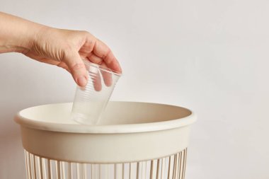 Plastik bardağı çöp kutusuna atan kişi. 