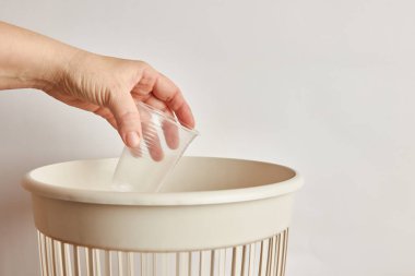 Plastik bardağı çöp kutusuna atan kişi. 