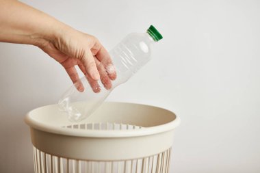 Plastik şişeyi çöp kutusuna atan kişi. 