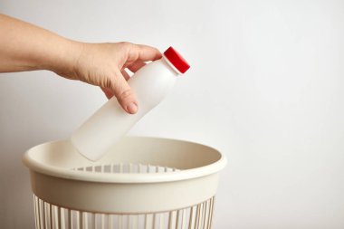 Plastik şişeyi çöp kutusuna atan kişi. 