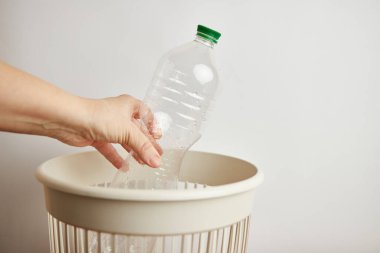 Plastik şişeyi çöp kutusuna atan kişi. 