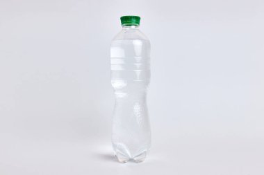 Beyaz zemin üzerinde su olan plastik şişe.