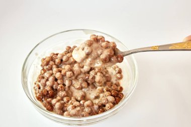 Kâsede kaşık ve beyaz arka planda sütle yemekler.