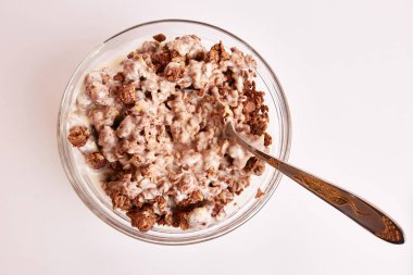 Kâsede kaşık ve beyaz arka planda sütle yemekler.