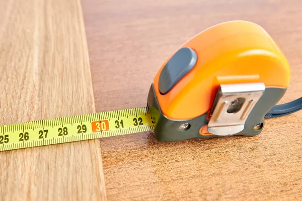 The length of a wooden board is measured with a tape measure