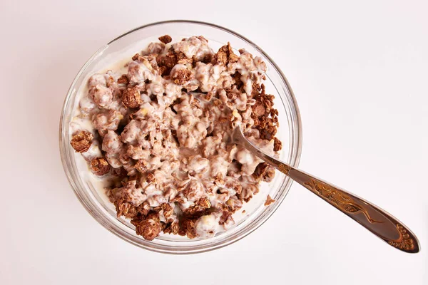 Kâsede kaşık ve beyaz arka planda sütle yemekler.