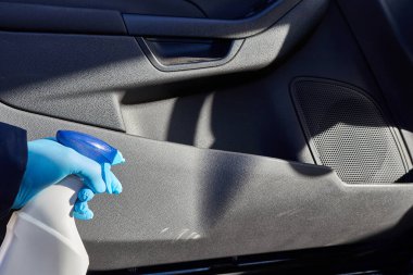 Bir adam arabayı deterjan ve bezle temizliyor. Araba temizleme konsepti.