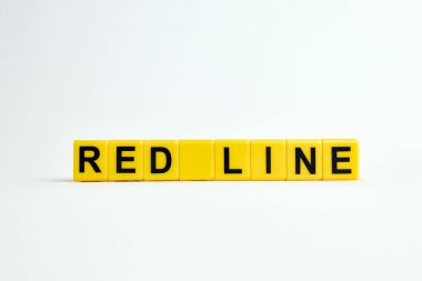 Beyaz zemin üzerinde sarı plastik bloklardan yapılmış kırmızı satır metni