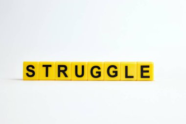 Beyaz zemin üzerinde sarı plastik bloklardan yapılmış mücadele metni