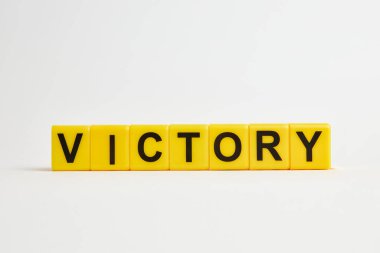 victoty text  made from  yellow plastic blocks on a white background