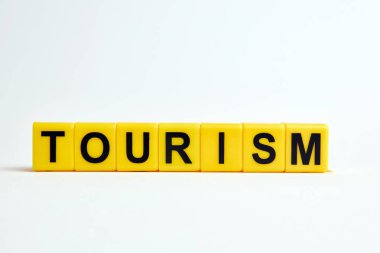 Beyaz zemin üzerinde sarı plastik bloklardan yapılmış turizm metni
