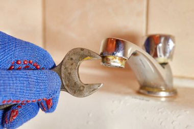 İşçi tuvaletteki musluğu tamir ediyor. 