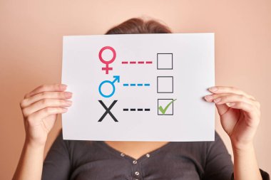 Elinde kağıt üzerinde cinsiyet anketi tutan genç bir kadın. 