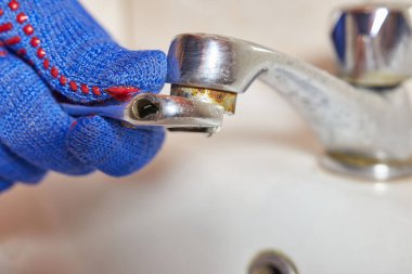 İşçi tuvaletteki musluğu tamir ediyor. 