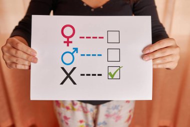 Elinde kağıt üzerinde cinsiyet anketi tutan genç bir kadın. 