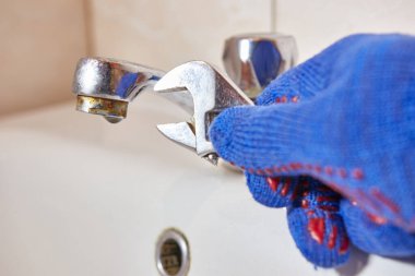 İşçi tuvaletteki musluğu tamir ediyor. 