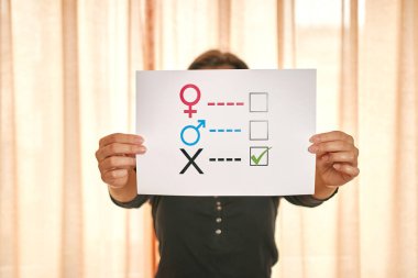 Elinde kağıt üzerinde cinsiyet anketi tutan genç bir kadın. 