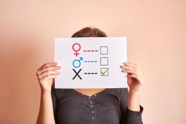 Elinde kağıt üzerinde cinsiyet anketi tutan genç bir kadın. 