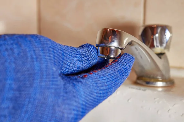 İşçi tuvaletteki musluğu tamir ediyor. 