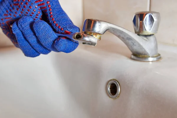 İşçi tuvaletteki musluğu tamir ediyor. 