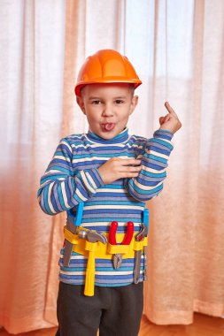 Çocuğun keyfi yerinde, oyuncak kaskı ve aletleri var..