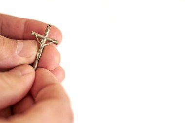 Beyaz arka planda haç tutan bir el. 