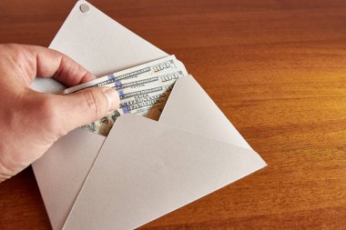 hand holding envelope with money on wooden table