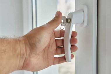 Pencere kolunu tutan bir adam. 