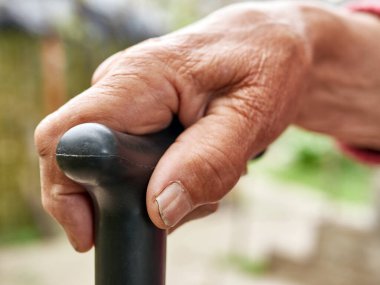 Yaşlı bir kadın hareket ederken sopasını tutuyor..