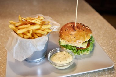 Kızarmış patates ve soslu hamburger pişirip servis etmek.