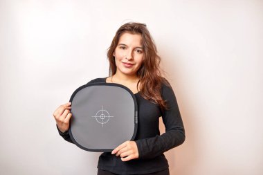 Gülümseyen güzel kız kameraya doğru renkleri kaydetmek için gri kart tutuyor..