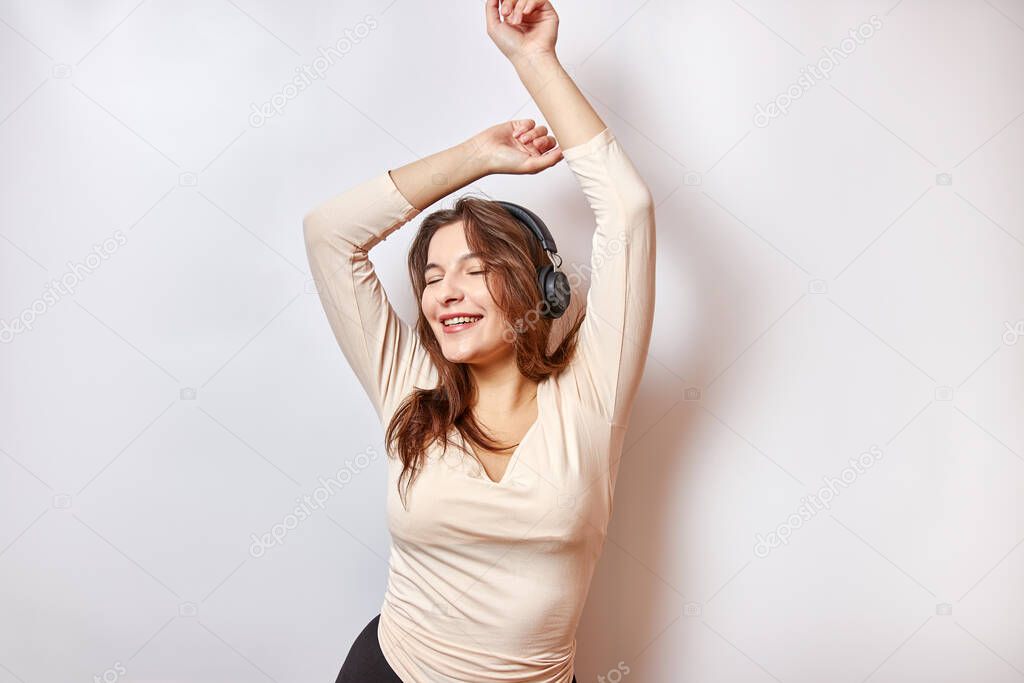 Beautiful girl with pleasure and a smile listens to music on headphones.