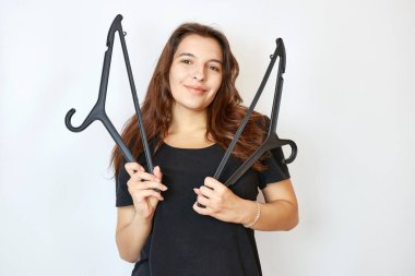 Siyah tişörtlü güzel bir kız iki askı tutuyor. Kıyafet alma konsepti.