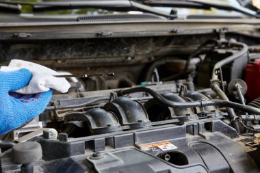 Bir adam arabanın motorundaki yağ seviyesini kontrol ediyor. Araba bakımı ve bakımı.