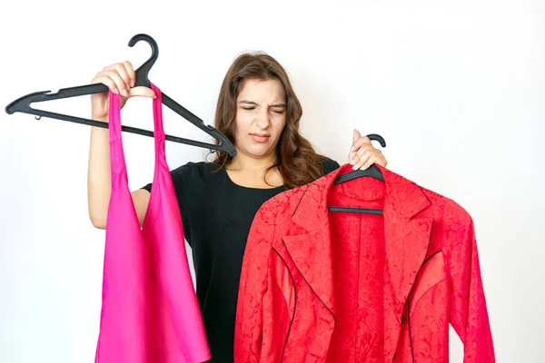 Beautiful girl dissatisfied with the choice of clothes on a hanger.