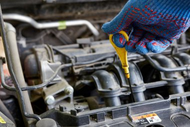 Bir adam arabanın motorundaki yağ seviyesini kontrol ediyor. Araba bakımı ve bakımı.
