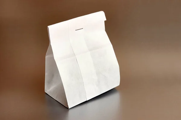 Paper bag with tea. Packing for dry products on a brown background.