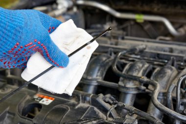 Bir adam arabanın motorundaki yağ seviyesini kontrol ediyor. Araba bakımı ve bakımı.