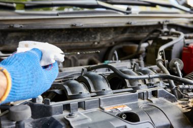 Bir adam arabanın motorundaki yağ seviyesini kontrol ediyor. Araba bakımı ve bakımı.