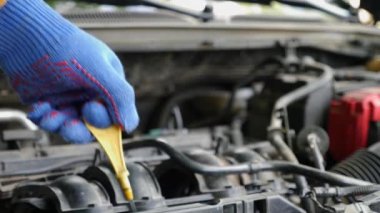 Bir adam arabanın motorundaki yağ seviyesini kontrol ediyor. Araba bakımı ve bakımı.