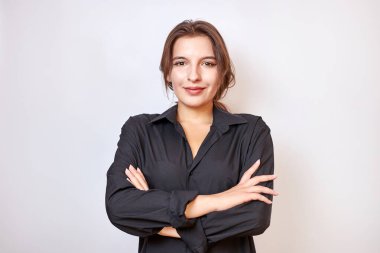 Siyah gömlekli güzel bir kız elleri önünde katlanmış duruyor..