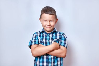 Kollarını kavuşturmuş, gülümseyen yakışıklı bir çocuk..