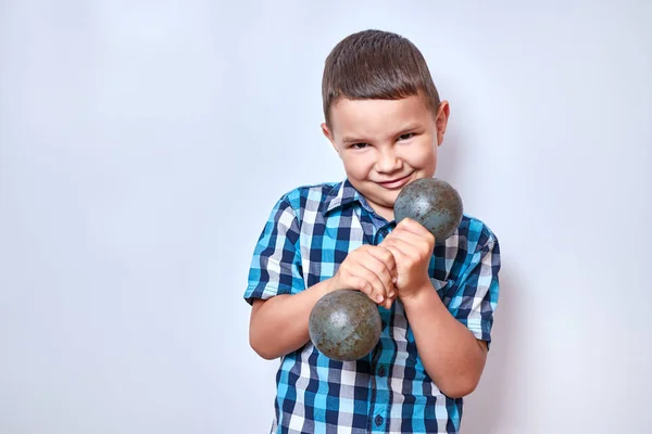 A boy tries to lift a heavy dumbbell. Fitness classes.